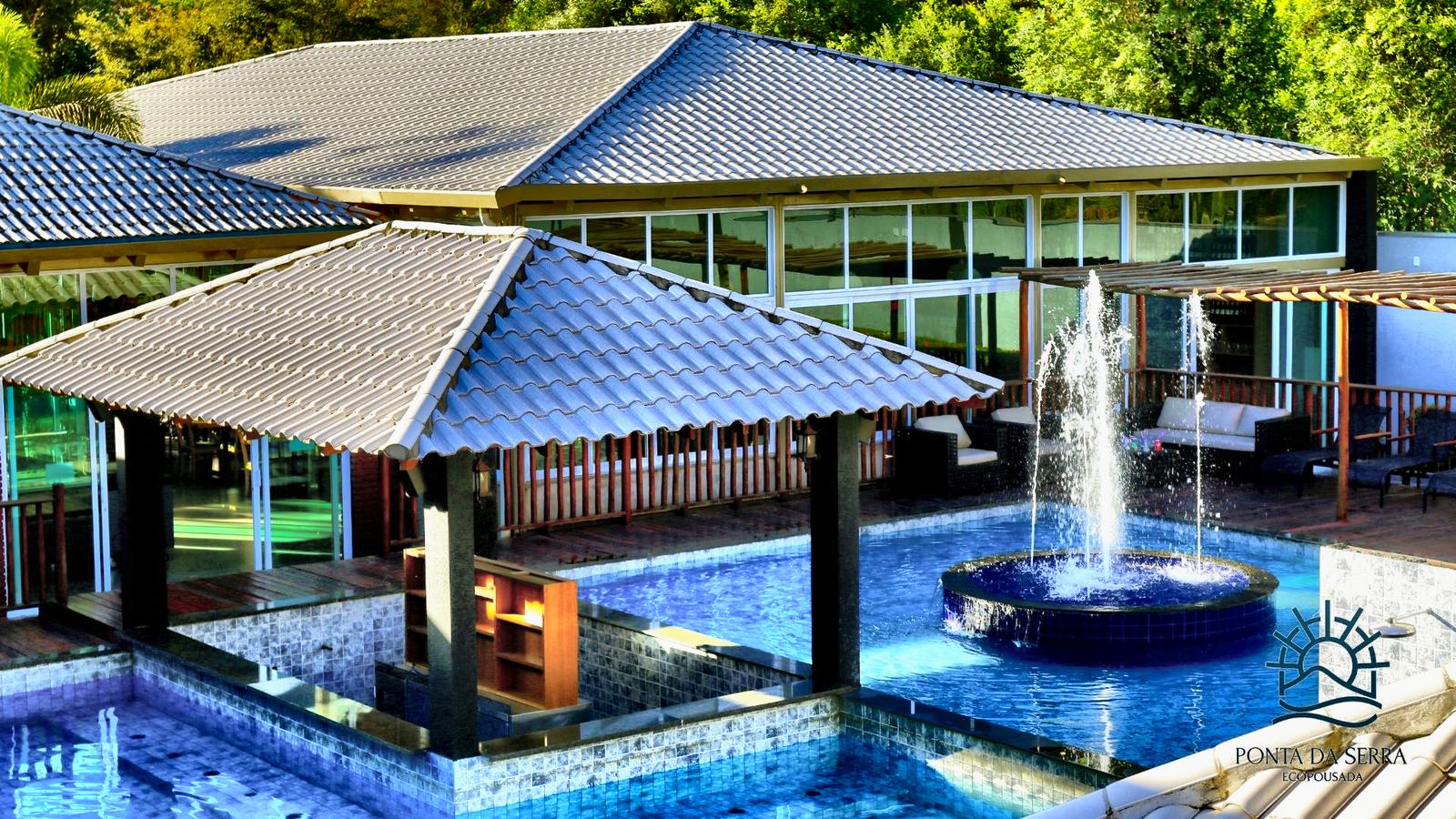 Piscina com fonte central, bar na água e quiosques cobertos